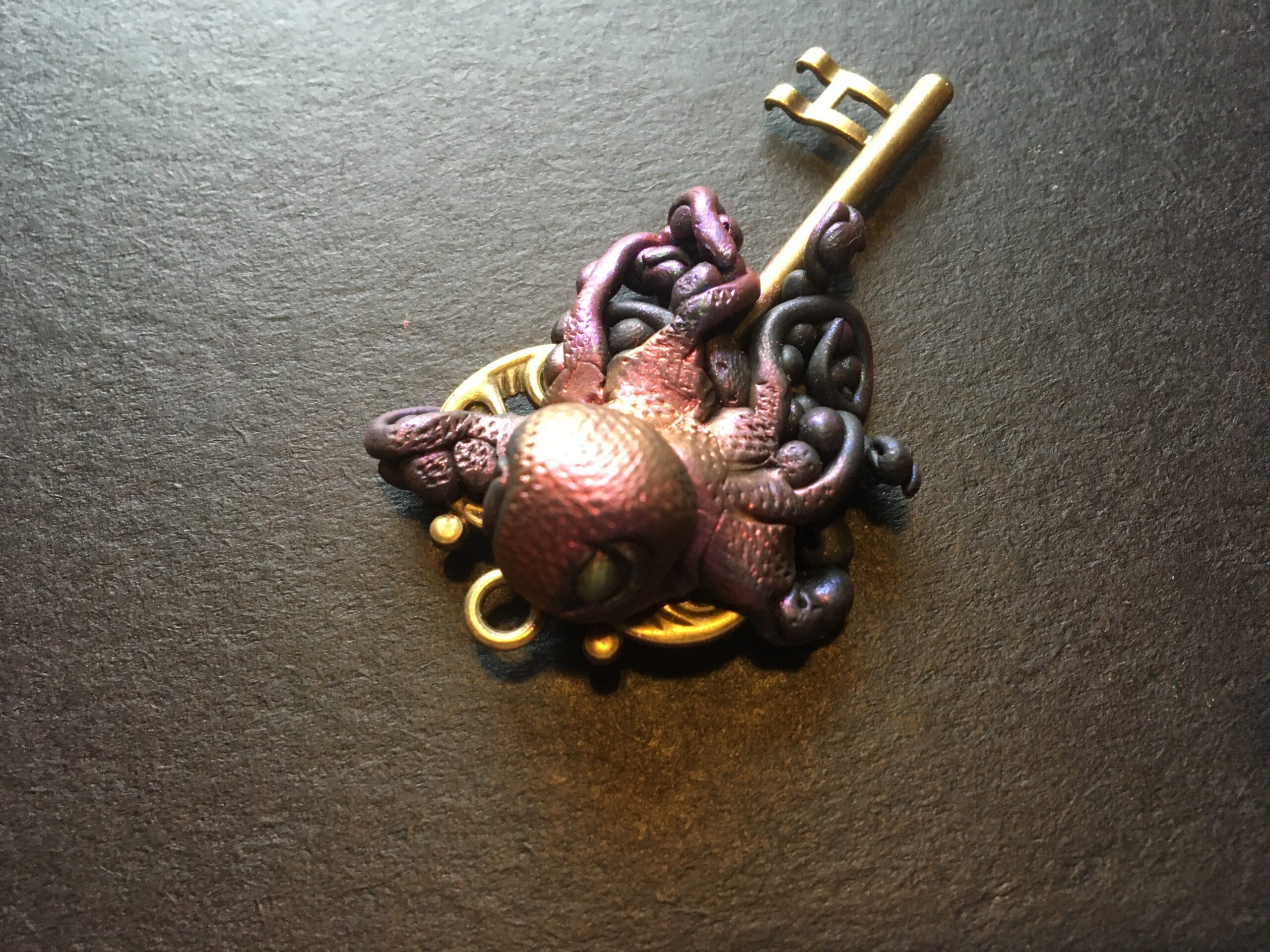 Polymer clay octopus intertwined around a brass key.