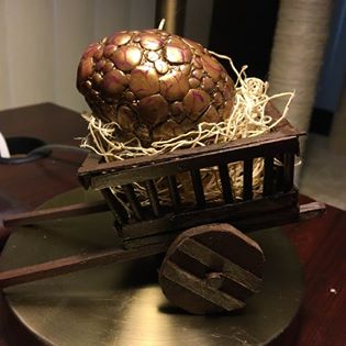 A "dragon egg" created from an emptied chicken egg and polymer clay. It sits in a medieval wheelbarrow filled with straw