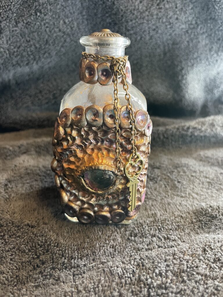 Dragon eye done in clay on a bottle, A small key hangs off the side